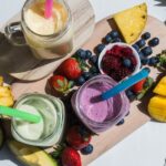 top view of hydrating foods for summer: colorful smoothie, healthy detox vitamin diet or vegan food concept, fresh vitamins, breakfast drink with avocado, pineapple, mango, strawberries, blueberries